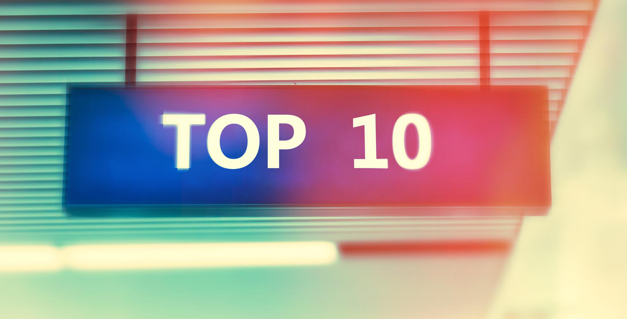 A rectangular blue sign with white text reading TOP 10 is displayed against a blurred background with horizontal lines and colorful light flares.